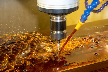 The CNC milling machine cutting the  mold parts with oil coolant method. The mold and die manufacturing process by CNC machining center. © Pixel_B