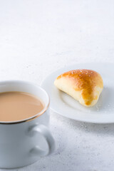 sugar bun and cup of milk tea on white textured background