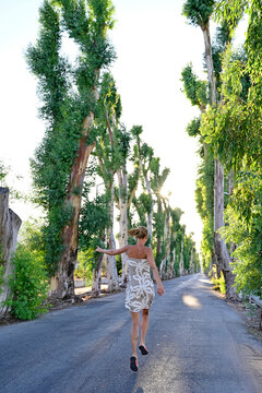 Greece, Dodecanese, Kolymbia, Adult woman hopping&Ocirc;&oslash;&Omega;merrily along eucalyptus avenue in summer