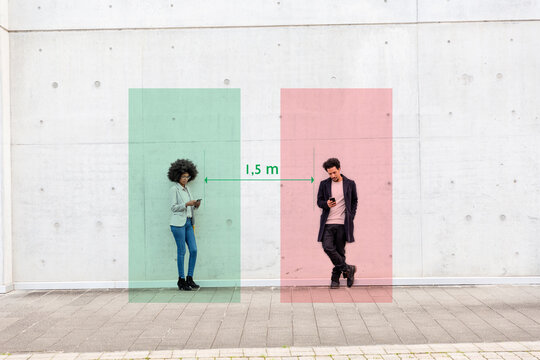 Rectangles visualizing social distancing covering man and woman standing outdoors with smart phones in hands