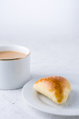 sugar bun and cup of milk tea on white textured background