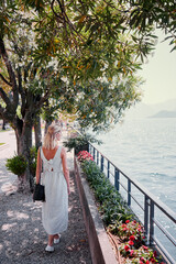 Travel by Italy. Young woman walking on the promenade of Como Lake.