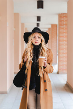Blond young woman with coffee cup standing at corridor