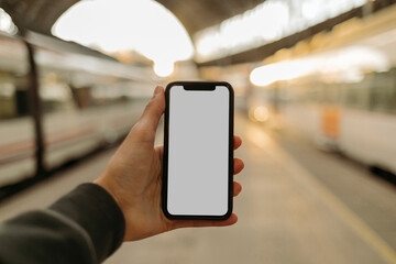 Young man using phone with blank screen at railroad station