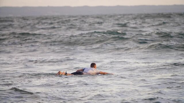Handheld Long Shot of Surfer Swimming Out to Sea