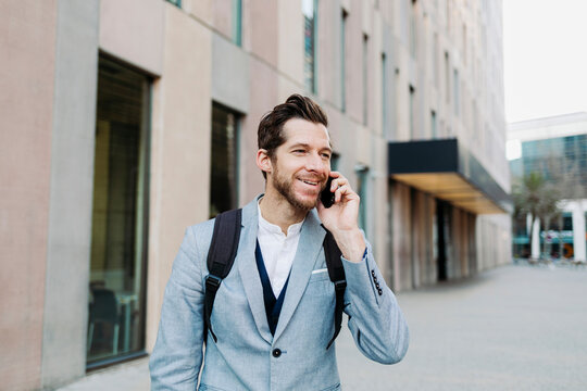 Smiling male professional talking on mobile phone while looking away