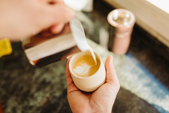 Young man preparing latte in kitchen