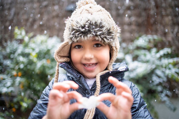 Cute smiling girl holding flower during snowfall