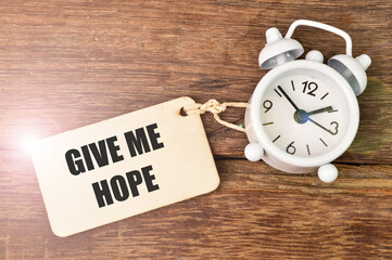 Top view of clock and wooden board written with GIVE ME HOPE.