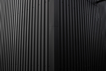 Black corrugated iron sheet used as a facade of a warehouse or factory. Texture of a seamless...