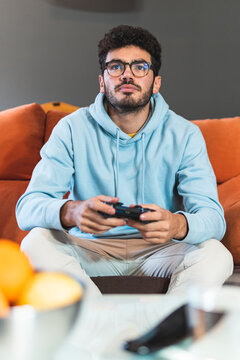 Concentrated young man playing video game in living room