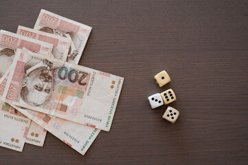 Pile of Croatian money banknotes (HRK) with couple of dices on wooden background. Risky investments...
