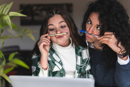 Playful mother and daughter puckering in front of digital tablet at home