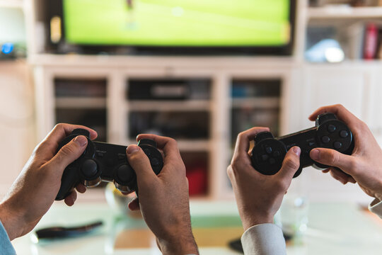 Male friends hands playing video game at home