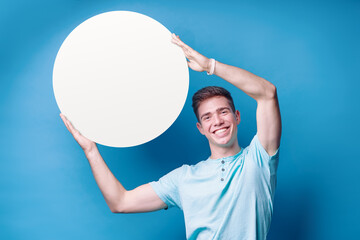 Your text here. Colorful studio portrait of handsome young man showing circle empty blank board...