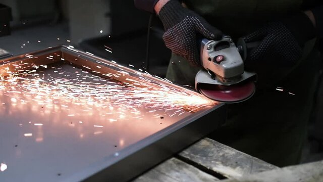 Worker grinding metal, metal grinding machine with sparks.  Super slow motion 240 fps