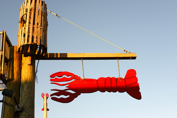 large lobster sculpture hanging on wooden post to advertise seafood restaurant