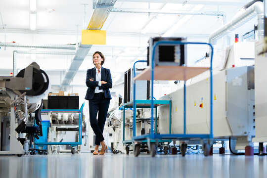 Female entrepreneur with arms crossed standing in factory