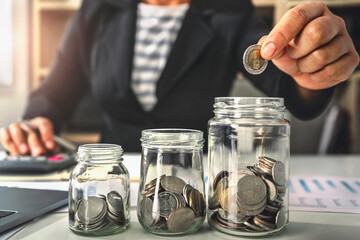 saving money with hand putting coins in jug glass concept financial