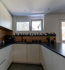 interior view of a modern and elegant kitchen with white cupboards and black tiles