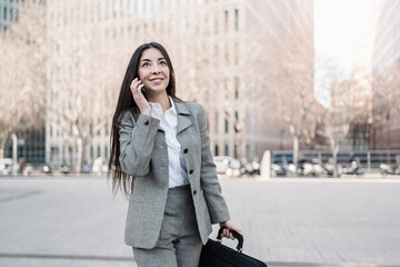 Smiling businesswoman talking on smart phone in city