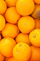 front view, close distance of a pile of local, ripe, freshly picked oranges on display and for sale at a tropical farmers market