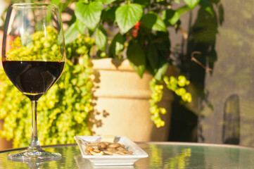front view, close distance of a wineglass with red wine and a rectangular plate with crackers on a glass table top