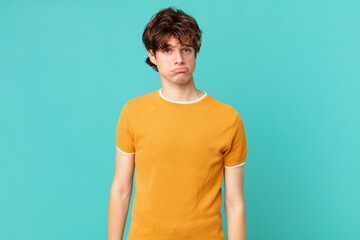 young handsome man feeling sad and whiney with an unhappy look and crying