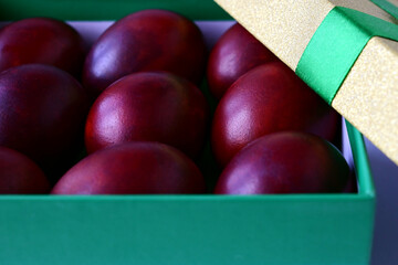 Easter colored red eggs are in a beautiful gift box. Easter symbol, holiday treat, gift