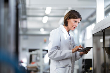 Mature female technician using digital tablet at laboratory