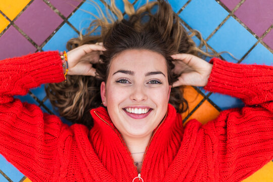 Smiling woman with hand in hair lying on tiled floor