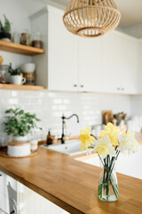 Fototapeta na wymiar daffodils bouquet in vase on the table white kitchen view