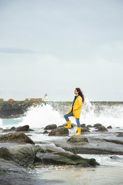 Young woman wearing yellow looking at view while standing on rock