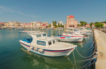 Obraz premium Port of charming Aegina town with yachts and fishermen boats docked in Aegina island, Saronic gulf, Greece, in a sunny summer morning