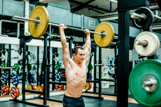 Shirtless man doing deadlift at health club