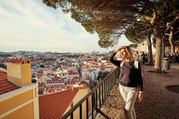 Traveling by Portugal. Young traveling woman enjoying old town Lisbon view, red tiled roofs and ancient architecture.