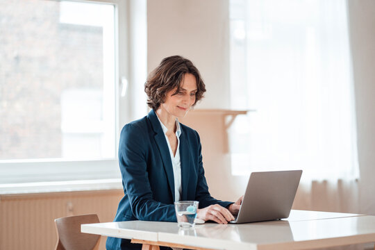Mature businesswoman using laptop on table at home office