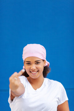 Smiling woman doing obscene gesture against wall