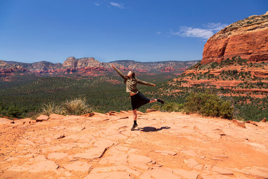 Female tourist dancing at Devil's Bridge Trailhead against sky on sunny day, Red Rocks, Sedona, Arizona, USA