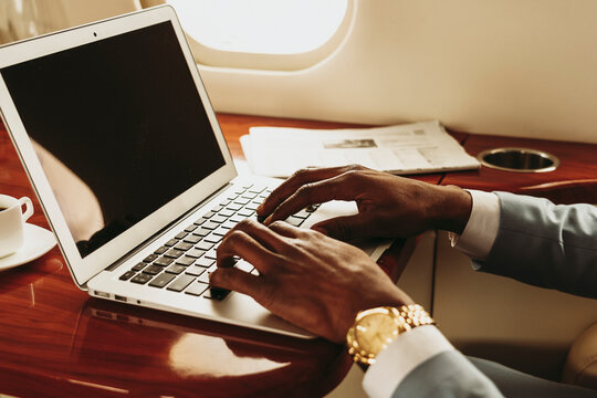 Businessman's hands typing on laptop in private jet