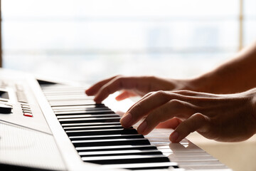 Close-up of male hands playing keyboard piano at home