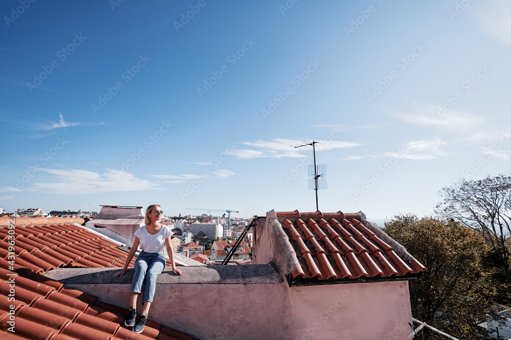 Wall mural Traveling by Portugal. Young traveling woman enjoying old town Lisbon view on red tiled roof.