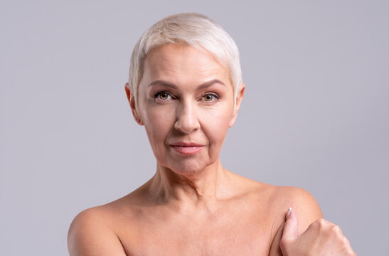 Senior woman staring while standing against gray background