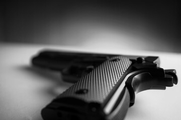 Black and white photo of big black gun pistol on white table.