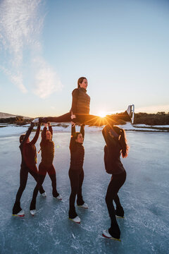 Female figure skaters practicing on frozen lake at sunset