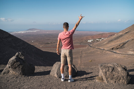 Male tourist gesturing horn sing at Femes viewpoint, Lanzarote, Spain