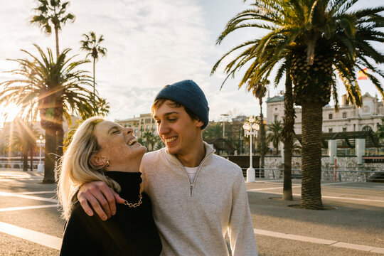 Cheerful young couple at promenade against sky