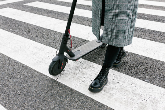 Woman with electric push scooter walking on Zebra Crossing