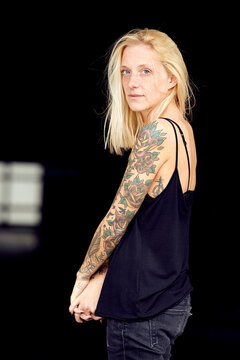 Tattooed woman with hands clasped at parking garage