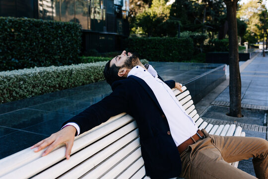 Businessman resting while leaning on bench